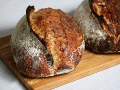 Two baked loaves of sourdough bread on cutting board