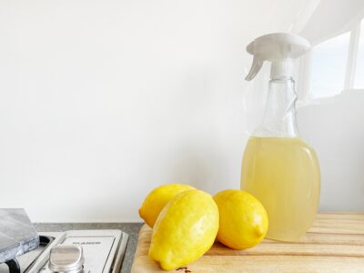 Whole lemons on counter next to spray bottle with lemon cleaning mix