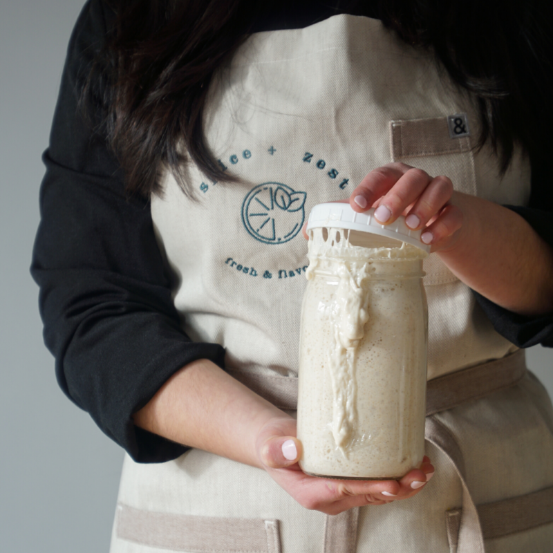 Woman holding overflowing sourdough starter in jar