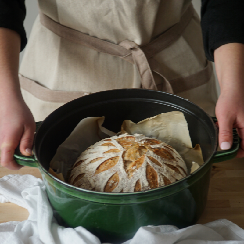 Woman holding baking pot with finished sourdough inside