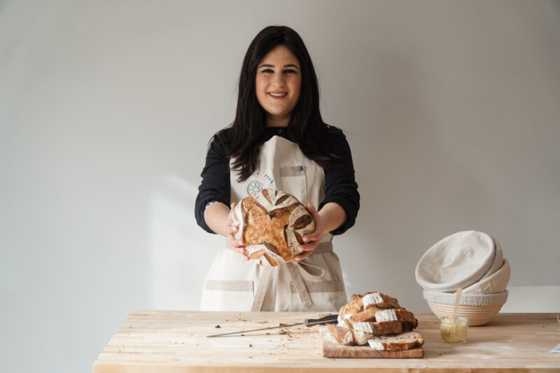 Sarah holding a loaf of sourdough bread that she baked 