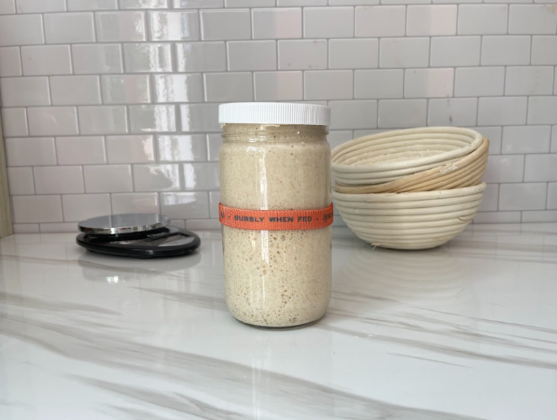 A jar of sourdough starter, a kitchen scale, and 3 bowls 