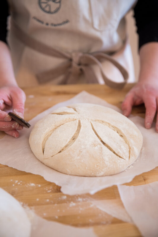 Scoring a raw loaf of sourdough